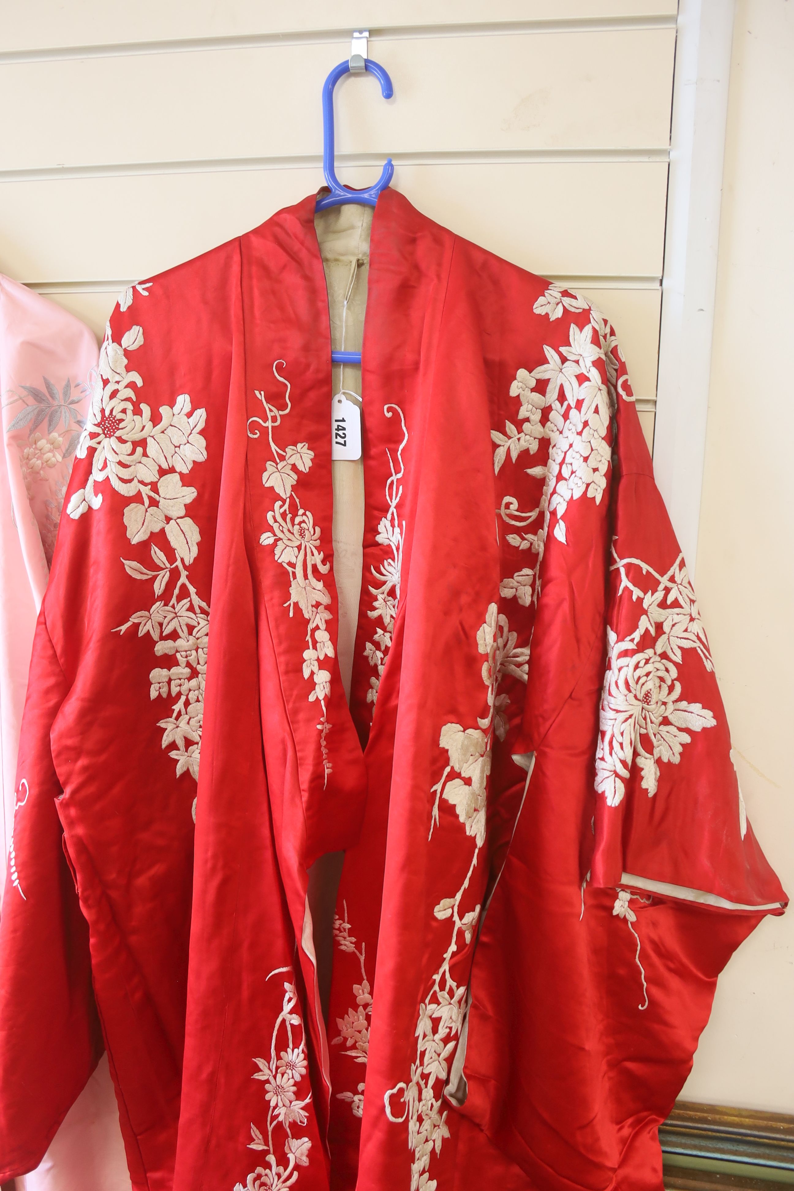 A pink silk Japanese kimono embroidered with wisteria and irises and butterflies, length 140cm, together with a red kimono embroidered with white wisteria and carnations